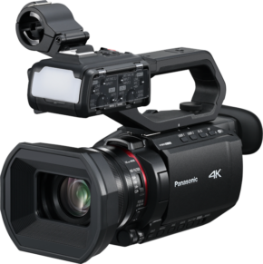 800q-01_131086 Mustassa Panasonic AG-CX18EJ -videokamerassa on suuri objektiivi, yläkahva, ulkoinen mikrofonikiinnike ja liitetyt äänisäätimet, jotka näkyvät vaalealla taustalla.