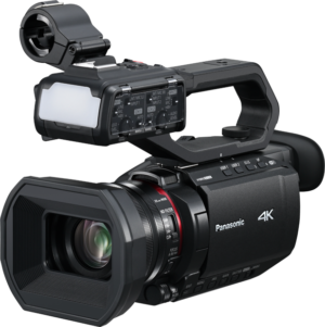 800q-01_131086 Mustassa Panasonic AG-CX18EJ -videokamerassa on suuri objektiivi, yläkahva, ulkoinen mikrofonikiinnike ja liitetyt äänisäätimet, jotka näkyvät vaalealla taustalla.