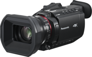Panasonic HC-X1600E -videokamera on esitetty mustana, ja siinä on suuri linssinsuojus, useita ohjauspainikkeita ja sivukahva, joka on sijoitettu pieneen kulmaan tavallista taustaa vasten.