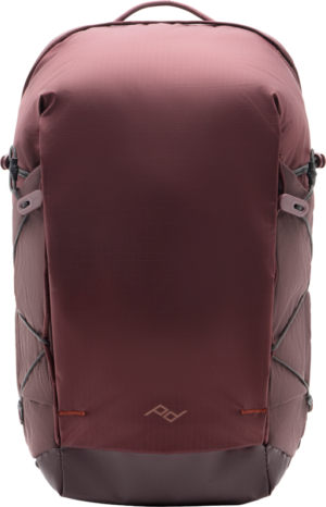 The Peak Design Outdoor Backpack Zip 18L Eclipse features a brown and dark grey minimalist design, side pockets, a small geometric front logo and elastic side straps for extra storage.
