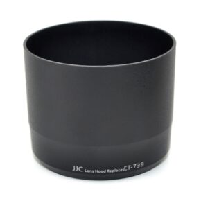 Musta lieriömäinen JJC ET 73B Canon -vastavalosuoja Musta mattapintainen linssinsuojus, jossa on valkoinen painatus "JJC Lens Hood Replaces ET-73B" lähellä pohjaa, kuvassa valkoista taustaa vasten.