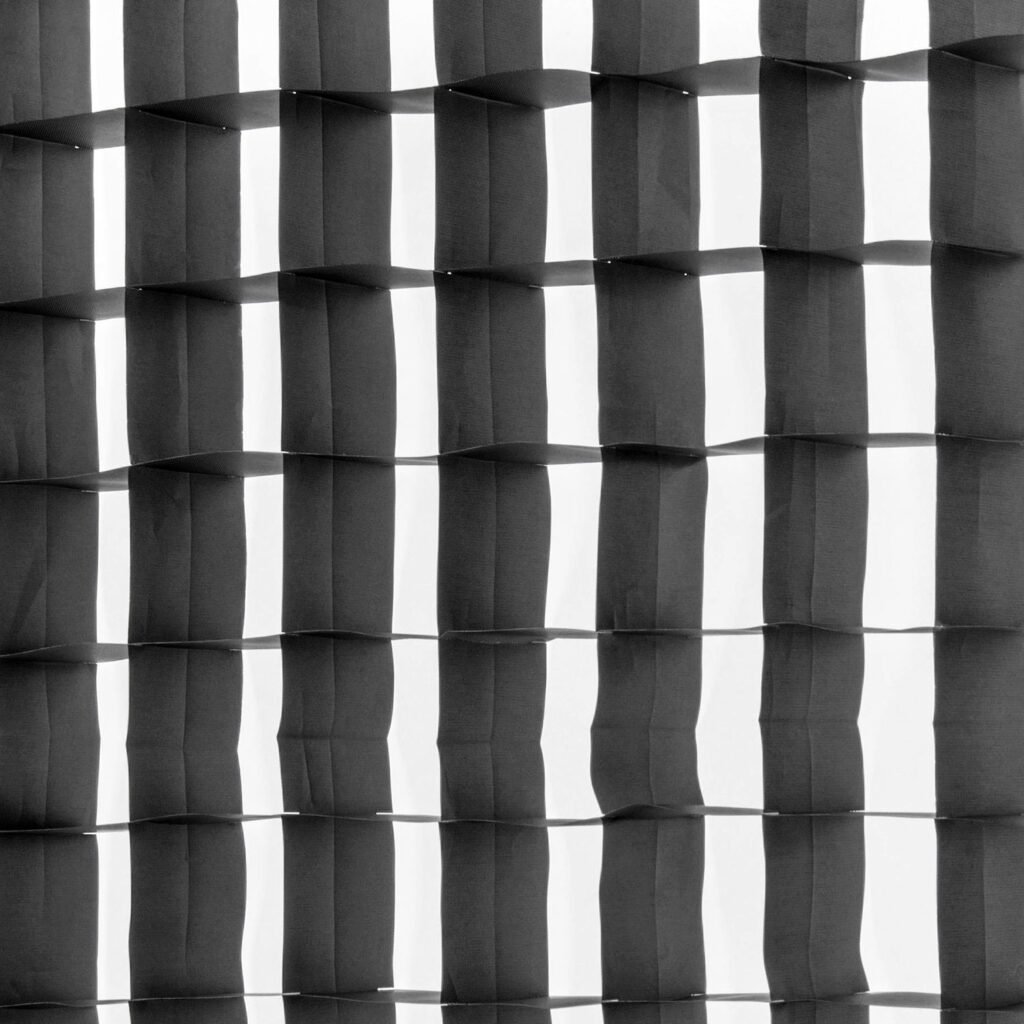 1643039207_361 Westcott 40 Degree Egg Crate Grid for Stripbank Switch & Stripbank luo mustavalkoisen abstraktin ruudukkokuvion, jossa varjot ja valo vuorottelevat ja joka tuottaa kolmiulotteisen, aaltoilevan pintaefektin.
