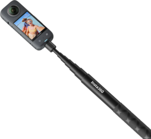 Insta360 114cm Invisible Selfie Stick mustassa värissä, johon on kiinnitetty 360 asteen toimintakamera, näyttää kaksi hymyilevää ihmistä näytöllään rannalla.