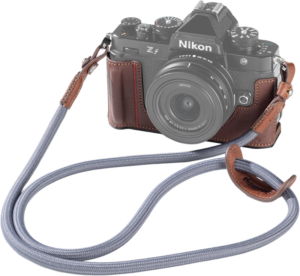 800q-01_134095 Nikon Z f -peilitön kamera, jossa on ruskea SmallRig 5096 -nahkakotelosarja ja harmaa kangashihna, näkyy valkoista taustaa vasten.