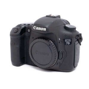 Canon EOS 7D-1 Musta Canon EOS 7D (SC 11000) - Käytetty kamerarunko ilman linssiä valkoisella pohjalla, jossa näkyy etupuoli ja vasen puoli, jossa näkyy kahva ja logo.