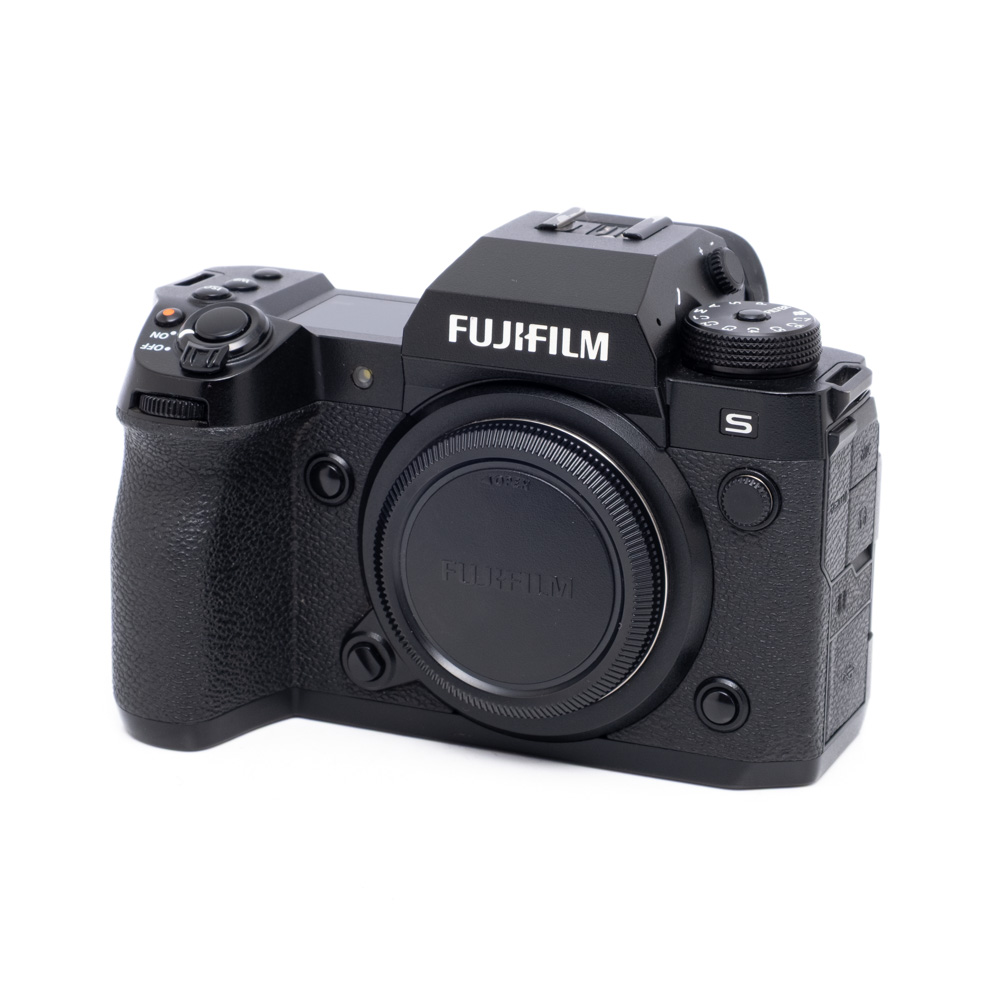 Fujifilm X-H2S-2C00498-1 Käytetty Fujifilm X-H2s (SC 9100, 12 kk takuu, sis. alv 25,5 %), musta kamerarunko, jossa on Fujifilmin logo ja erilaisia säätimiä ja painikkeita ylä- ja sivupuolella, ilman objektiivia.