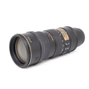 Nikon 70-200mm f2.8G VR ED-2 Nikon AF-S Nikkor 70-200mm f/2.8G VR ED - Käytetty on musta DSLR-zoom-objektiivi, jossa on kuvioidut tarkennus- ja zoomausrenkaat, kultainen etiketti ja useita kytkimiä valkoisella pohjalla.
