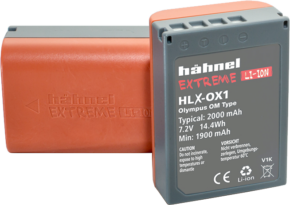 Kuvassa on kaksi harmaata ja oranssia Hähnel Battery Extreme Olympus HLX-OX1 / BLX-1 -akkuakkua: toinen on pystyssä ja näyttää etikettinsä ja tekniset tiedot, kun taas toinen makaa litteänä taustalla.