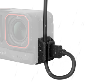 800q-01_133849 Lähikuva Insta360 All-Weather USB Charging Cover Ace Pro 2/Ace Pro -liitinsuojasta, jonka kaapelissa ja liittimessä on vesipisaroita, mikä korostaa sen vedenkestävää rakennetta. Kameran linssi ja runko näkyvät hieman epäselvästi taustalla.