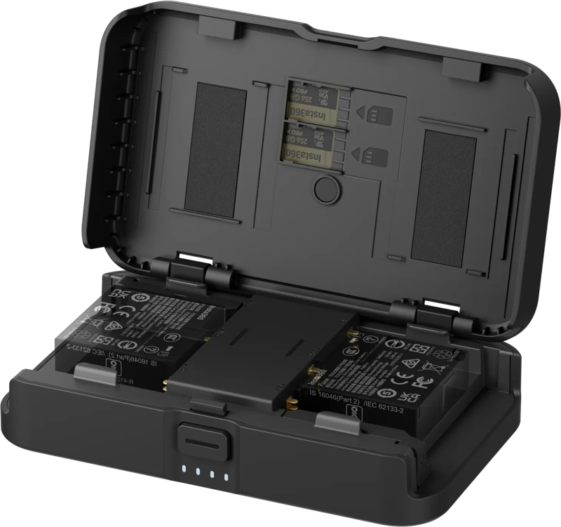 800q-01_133896 Insta360 Portable Charging Case -latauskotelo -latausasema on avattu, jolloin sen sisältä paljastuu kaksi akkua. Etupuolella on neljä LED-merkkivaloa, ja sisäkannessa on merkittyjä paikkoja akkujen oikeaa sijoittamista varten.