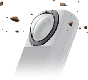 800q-01_133910 Lähikuva Insta360 X3 Premium Removable Lens Guards -linssisuojasta, valkoinen, jossa on laaja linssi, jota ympäröivät lentävät kivet vaaleanharmaalla taustalla, korostaen sen kestävää ja karua suojaa.