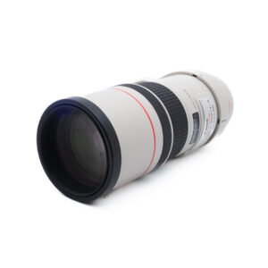 Canon EF 300mm f/4 L IS USM (Kunto K5, Takuuta 6kk) - Käytetty on valkoinen teleobjektiivi, jossa on musta tarkennusrengas ja punainen aksentti, joka näkyy valkoisella pinnalla korostaen etulasin ja piipun yksityiskohtia.