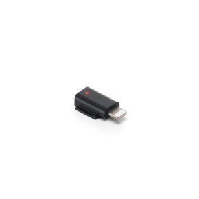 DJILighting DJI Mic 3 -matkapuhelinsovitin (Lightning) -puhelinadapteri on kompakti musta sovitin, jossa on metallinen liitin ja pieni punainen kolmio valkoisella pohjalla.
