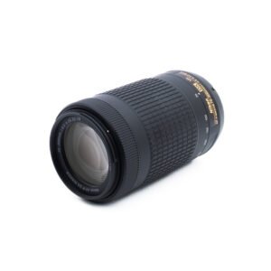 Musta Nikon AF-P Nikkor 70-300mm f/4.5-6.3G ED DX VR (Kunto K5) - Käytetty zoom-objektiivi on sijoitettu vinosti valkoiselle taustalle, ja etulasi ja zoomin merkinnät näkyvät selvästi.