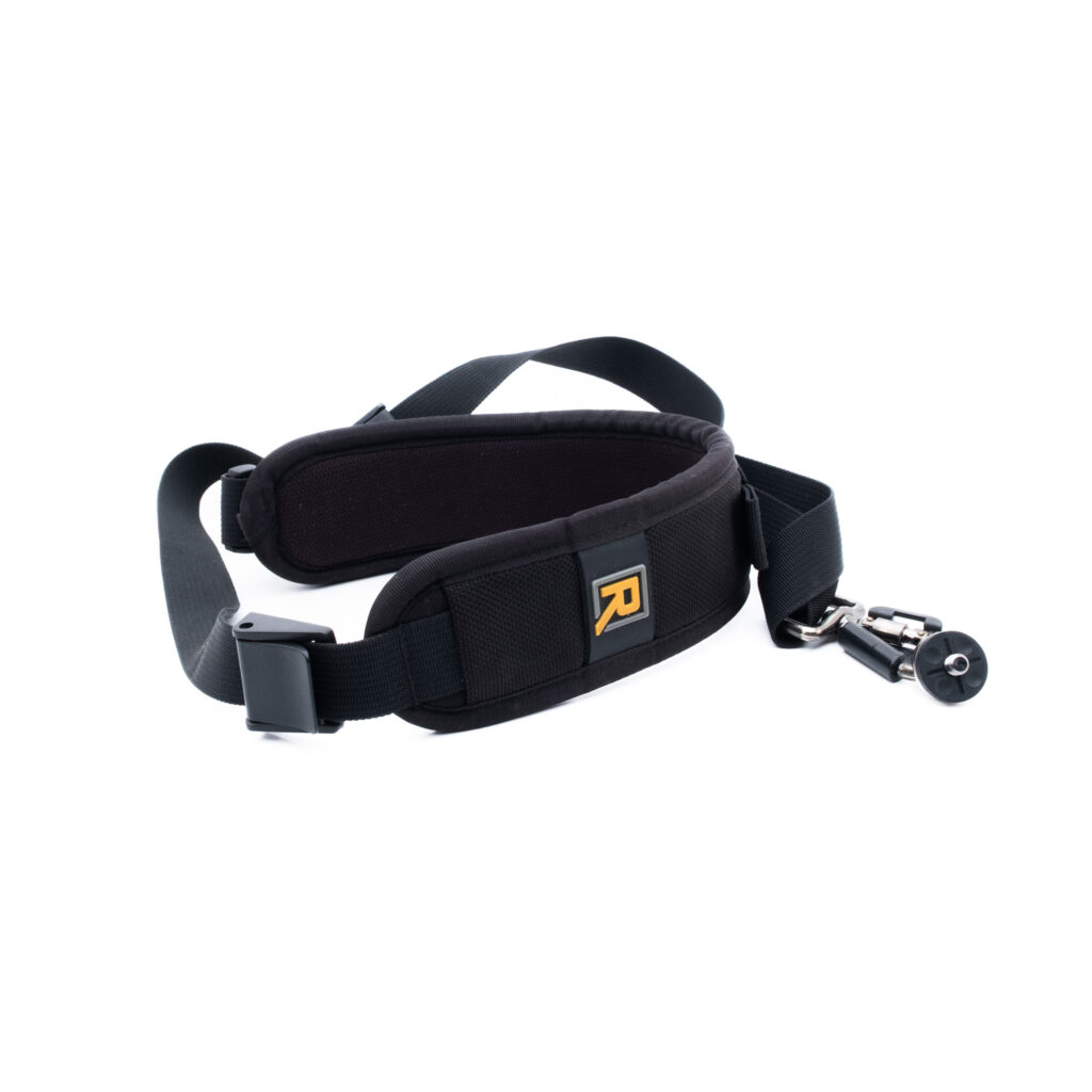Blackrapid RS-7 BlackRapid RS-7 Curve Sling -kamerahihnassa - Käytetty on musta pehmustettu muotoilu, säädettävä nailonhihna, metallinen kääntökoukku ja keltainen R-logo tyynyssä valkoista taustaa vasten.
