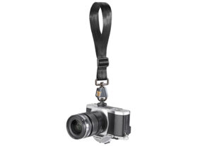 A black and silver digital camera with a large lens is attached to a BlackRapid wrist strap with an FR-5 Breathe camera strap hanging vertically against a white background.