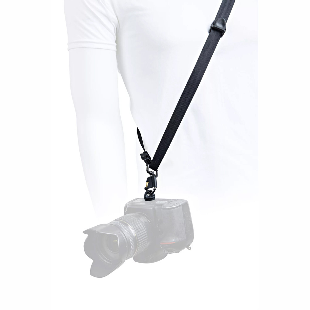 © BryCox.com, Bry Cox Valkoiseen paitaan pukeutunut henkilö käyttää BlackRapid Blackline I Right Camera Sling-kamerahihnaa, jossa DSLR-kamera roikkuu hänen vierellään. Tausta on valkoinen ja kuvan alaosa on häivytetty.