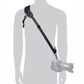 Siluetti käyttää BlackRapid Blackline I Left Camera Sling -kamerahihnaa, mustaa ristikkäishihnaa, jossa on säädettävä olkatuki ja metallinen liitin, joka kiinnittää lantiolla roikkuvan kameran.