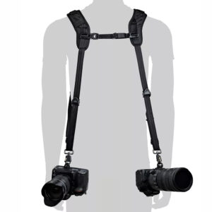 1711443116_247 Siluetti henkilöstä, jolla on BlackRapid Blackline II Double Camera Harness -kamerahihna ja joka kantaa kahta mustaa DSLR-kameraa lantion korkeudella, yksi kummallakin puolella.