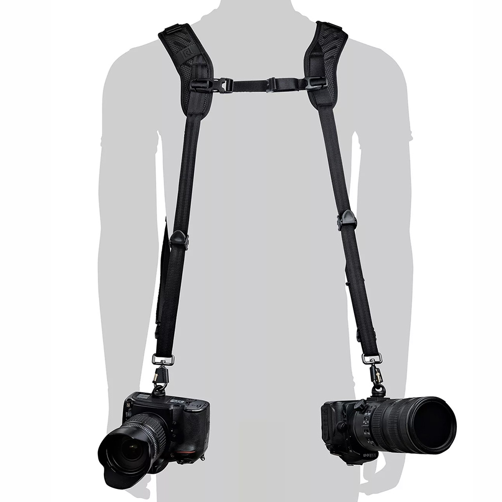 1711443116_247 Silhouette of a person wearing a BlackRapid Blackline II Double Camera Harness and carrying two black DSLR cameras at hip height, one on each side.