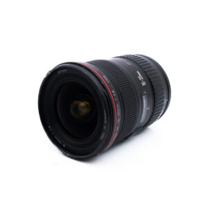 Canon 16-35mm f28 L USM-2 Musta kameran objektiivi, jossa on punavalkoiset merkinnät 16-35mm, lepää valkoisella pohjalla, vinossa kuvattuna niin, että etulasin elementti ja objektiivin rungon yksityiskohdat näkyvät.