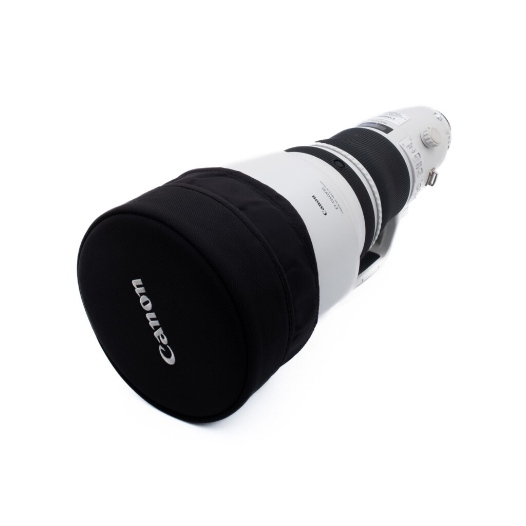 Canon 400mm f28 L IS II USM-4 Suuri Canon-telekameran objektiivi, jossa on musta suojakotelo, kuvattuna kulmassa valkoisella taustalla. Objektiivi on valkoinen mustilla korostuksilla, ja siinä on näkyvissä ohjauskytkimet ja tuotemerkki.