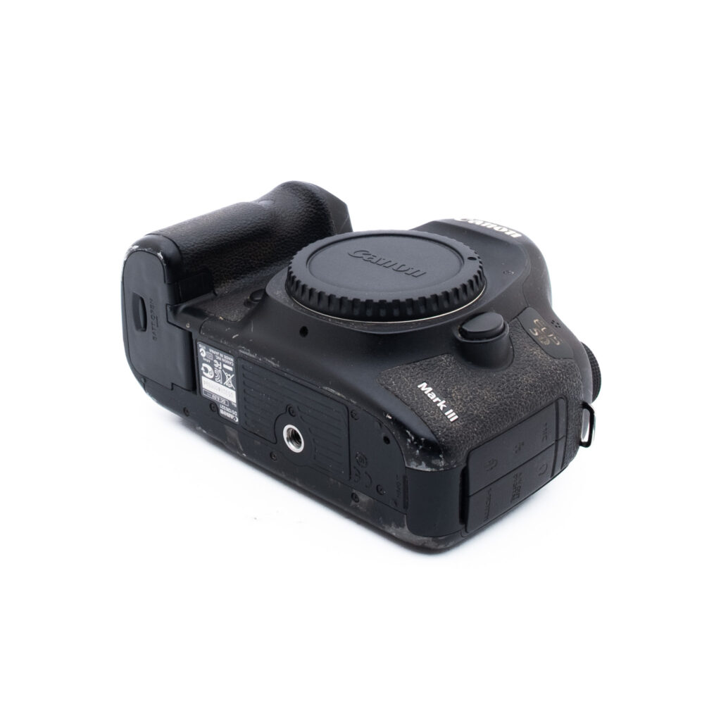 Canon 5D Mark III-1 Musta Canon Rebel T3i DSLR-kameran runko, jossa on näkyviä kulumia ja naarmuja, valkoisella pohjalla. Objektiivi ei ole kiinnitetty, ja kamera on asetettu kulmaan, jossa sen sivu ja pohja näkyvät.