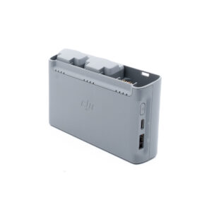 DJI Mini 2 SE-1 Harmaa DJI:n akkujen latauskeskitin, johon on asetettu kaksi akkua ja jonka sivulla on USB- ja USB-C-portit valkoista taustaa vasten.