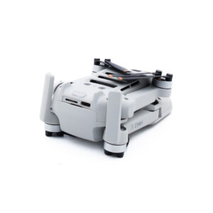 DJI Mini 2 SE-3 Pienikokoinen, kokoontaitettu harmaa lennokki, jossa on näkyvät potkurit ja kamerakotelo valkoisella pohjalla.