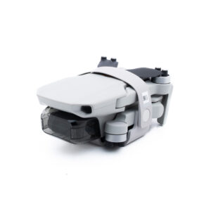 DJI Mini 2 SE-5 Pienikokoinen, kokoontaitettu valkoinen lennokki, jossa on harmaita aksentteja ja joka on kiinnitetty lukitushihnalla ja jonka potkurit on sijoitettu siististi sivuille.