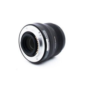Fuji 23mm f2 R WR-1-2 Musta kameran linssi kyljellään, jossa näkyy metallikiinnitys ja elektroniset koskettimet valkoista taustaa vasten.