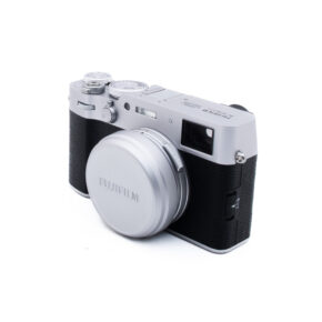 Fuji X100VI-5-3 Hopeanmusta Fujifilm-digitaalikamera, jossa on objektiivin suojus, kuvattuna kolmen neljäsosan kulmassa valkoista taustaa vasten.