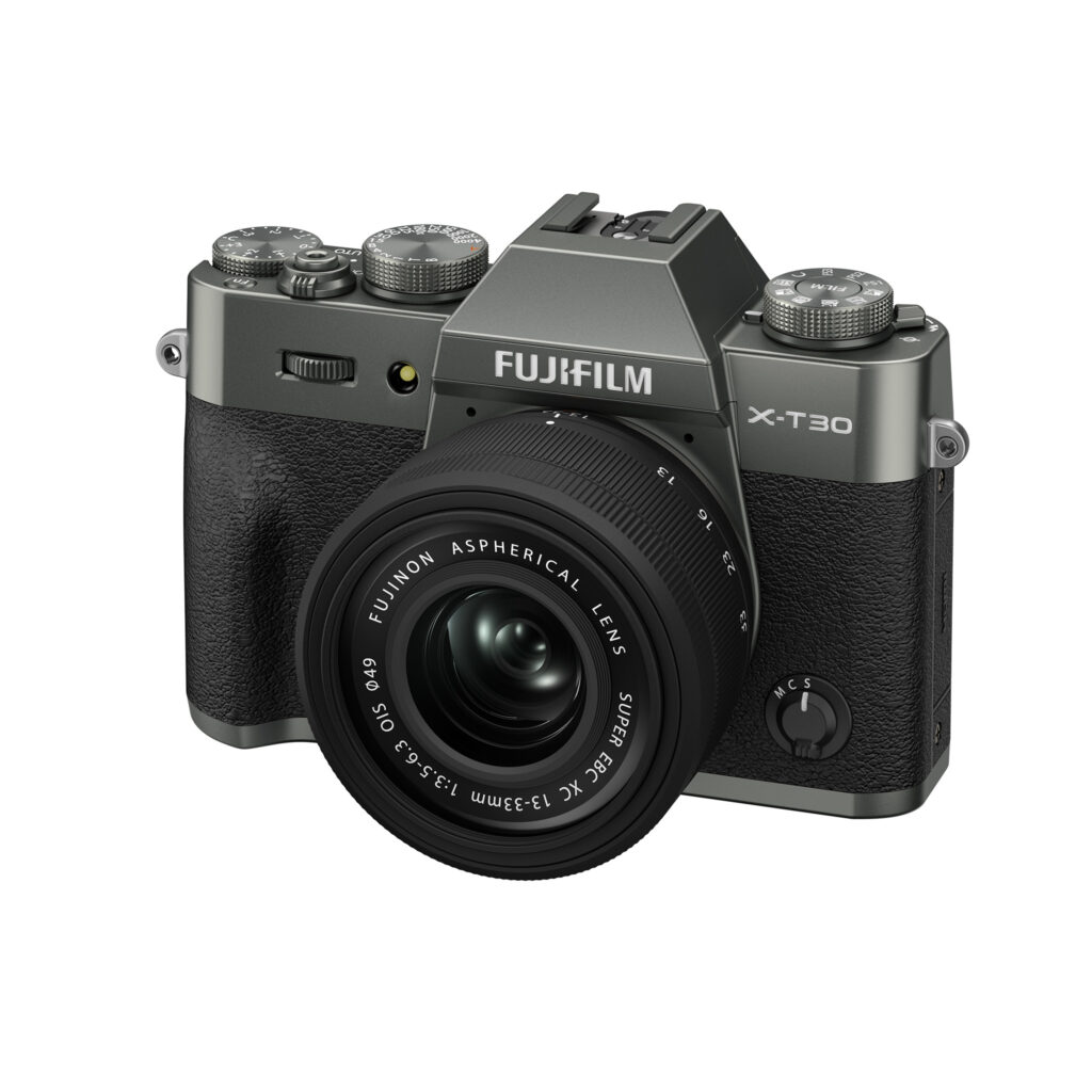 FujiX-T30IIIHarmaaLinssi2 Harmaa Fujifilm X-T30 III -digitaalikamera, jossa on XC 13-33mm f/3.5-6.3 OIS -objektiivi, näkyy kuvakulmassa valkoista taustaa vasten.