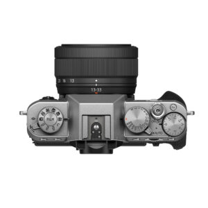 FujiX-T30IIIHopealinssi3 Fujifilm X-T30 III (hopea) -digitaalikameran yläkuva mustalla XC 13-33mm f/3.5-6.3 OIS -objektiivilla, jossa näkyy selkeät hallintalaitteet, toimintatilan ja suljinnopeuden valitsimet sekä oikealla puolella oleva kuvioitu kahva.