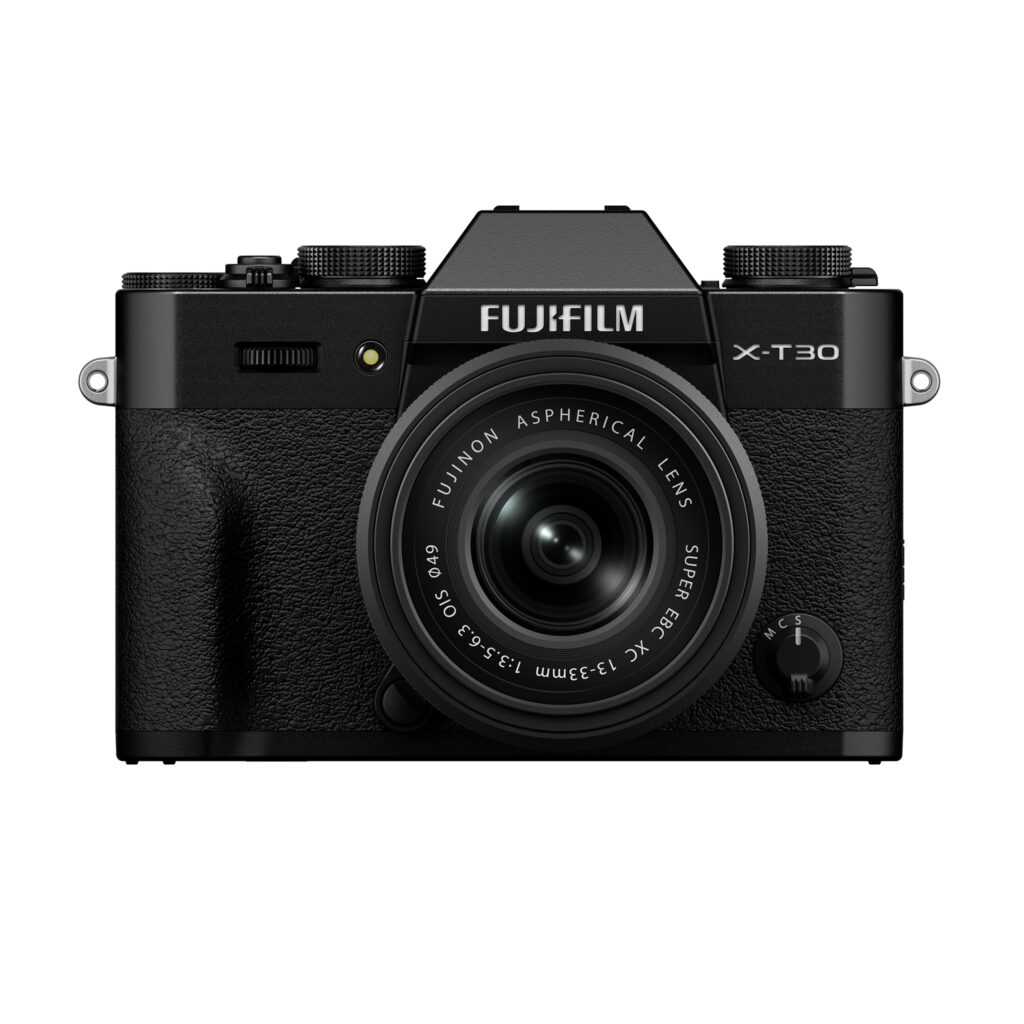 FujiX-T30IIIMustaLinssi1 Musta Fujifilm X-T30 III -peilitön digitaalikamera, jossa on XC 13-33mm f/3.5-6.3 OIS -objektiivi, edestä kuvattuna valkoista taustaa vasten.