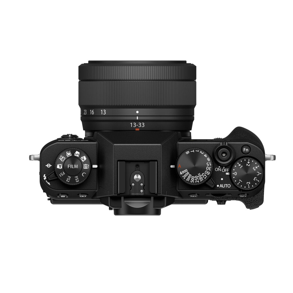 FujiX-T30IIIMustaLinssi4 Fujifilm X-T30 III + XC 13-33mm f/3.5-6.3 OIS, musta, ylhäältä katsottuna, jossa on valintakiekot suljinnopeudelle, valotuksen kompensoinnille ja kuvaustiloille, objektiivi polttovälin merkinnöillä ja kuvioitu oikeanpuoleinen kahva.