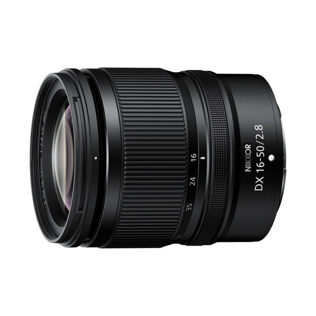 NikkorDX16-50 Nikon Nikkor Z DX 16-50mm f/2.8 VR -objektiivi näkyy vinossa valkoisella taustalla, jossa korostuvat objektiivin lasi, tarkennusrengas ja tynnyrin merkintä.