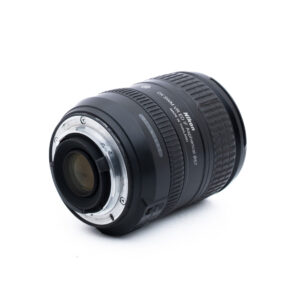 Nikon 16-85mm f35-56G ED DX VR-1 Nikon DX SWM VR 18-55mm -kameran objektiivi näkyy valkoisella pohjalla, ja se on asetettu kulmaan niin, että metallinen kiinnitys ja objektiivin yksityiskohdat näkyvät.