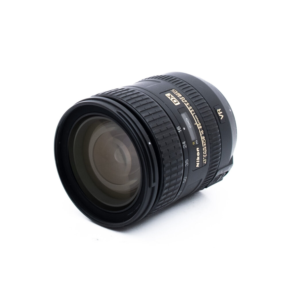 Nikon 16-85mm f35-56G ED DX VR-2 Nikon-kameran zoom-objektiivi, jossa on musta runko ja jossa on merkinnät kuten "DX", "VR" ja "AF-S NIKKOR 18-105mm". Objektiivi on hieman kallistettu, jolloin sekä lasi että ohjausrenkaat tulevat näkyviin.