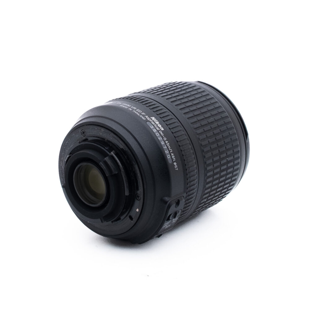 Nikon 18-105mm f35-56 G ED DX VR-1 Musta kameran objektiivi on kyljellään valkoista taustaa vasten, ja siinä näkyy takakiinnitys ja kuvioitu zoomausrengas.