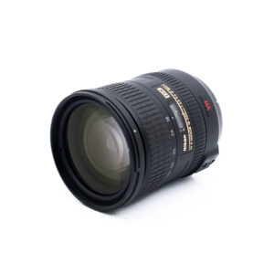 Nikon 18-200mm f35-56 G ED DX VR-2 Musta Nikon-kameran objektiivi, jossa on kultainen ja valkoinen merkintä, näkyvät tarkennus- ja zoomausrenkaat sekä suuri etulasi, valkoisella taustalla.