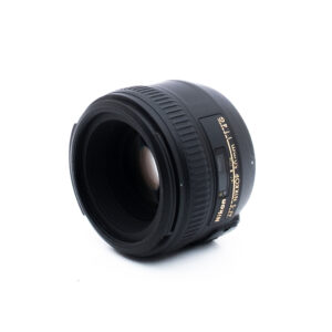 Nikon AF-S NIKKOR 50mm f/1.8G -kameran objektiivi näkyy valkoista taustaa vasten, ja se on suunnattu niin, että etulasi ja sivumerkintä näkyvät.