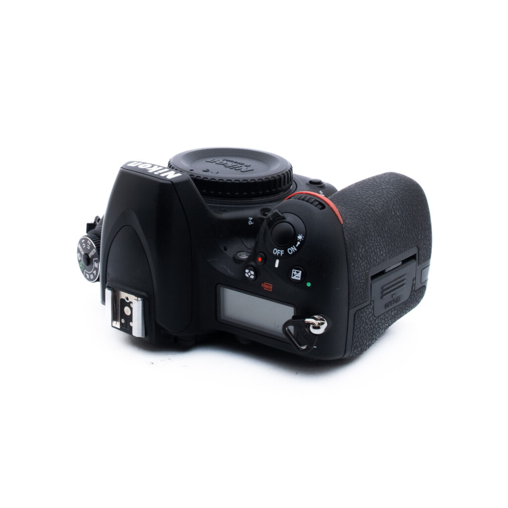 Nikon D750 5512-2 Musta Nikonin DSLR-kameran runko näkyy ylhäältä päin valkoisella pohjalla, ja siinä näkyvät toimintatilan valitsin, suljinpainike, nestekidenäyttöpaneeli ja kahva. Objektiivia ei ole kiinnitetty.