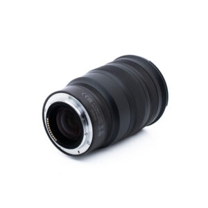 Nikon Z 24-70mm f28 S-1-2 Musta kameran zoom-objektiivi, jossa on kuvioitu kahva, metallinen kiinnitysrengas ja elektroniset koskettimet, sijoitettu vinoon valkoiselle taustalle.