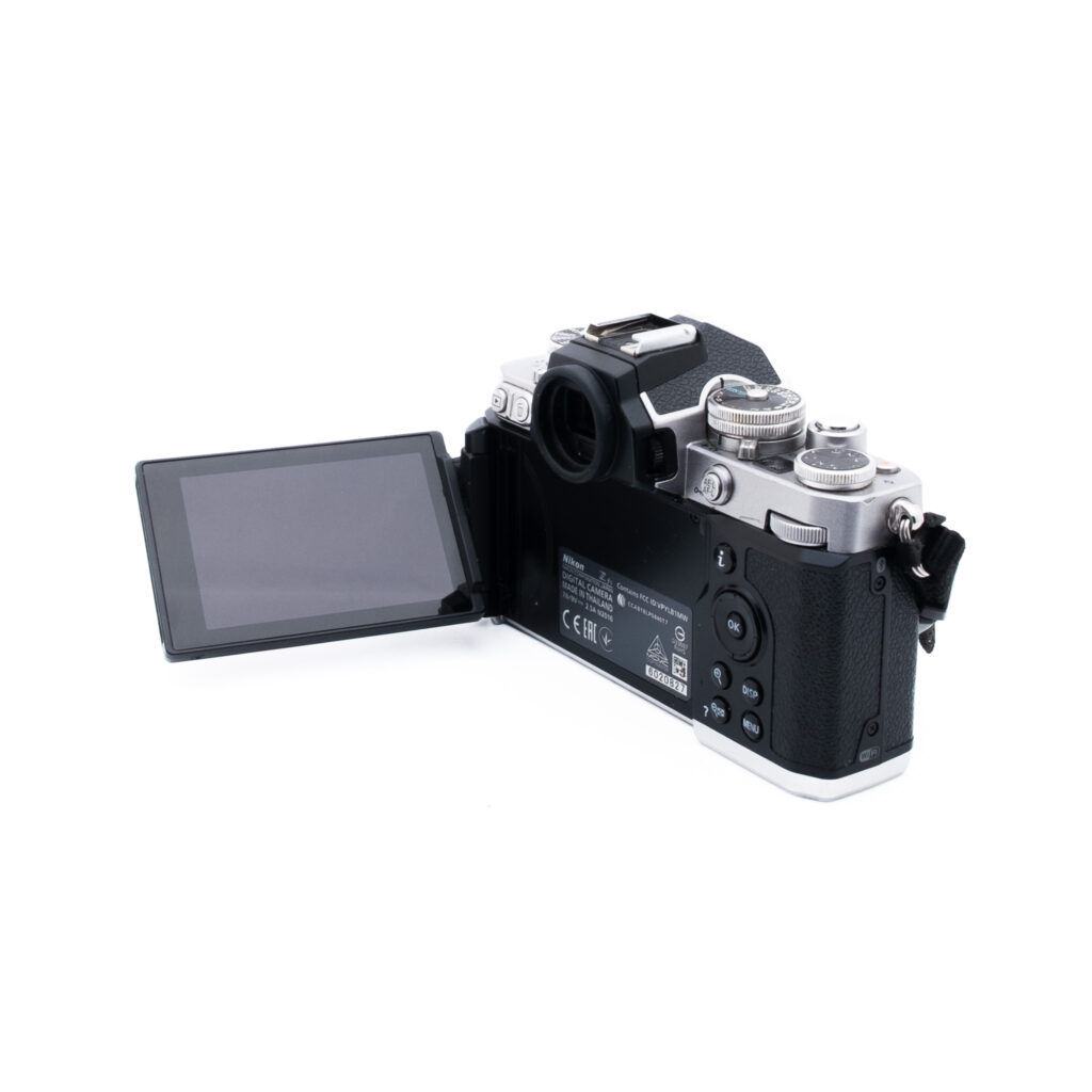 Nikon Z fc-3 Nikon Z fc (SC 6500) - Käytetty on digitaalikamera, jossa on vasemmalle ulosvedettävä LCD-näyttö, joka paljastaa takasäätimet, etsimen ja sen tyylikkään mustan ja hopeanvärisen rungon, jossa on näkyvät säätimet ja painikkeet.