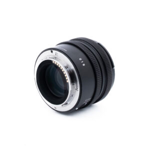 Sigma 45mm f28 DG DN Sony-1 Kameran objektiivi, jossa on metallinen kiinnitys, on sijoitettu valkoiselle taustalle, ja sen takaosa, elektroniset koskettimet ja tarkennusrengas näkyvät. Objektiivi on musta, ja kiinnikkeen ympärillä on hopeisia yksityiskohtia.