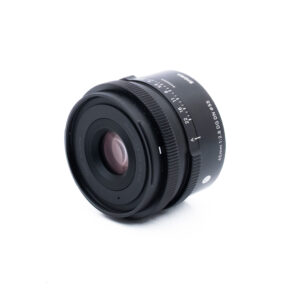 Sigma 45mm f28 DG DN Sony-2 Musta kameran objektiivi, jossa on valkoinen teksti, mukaan lukien tiedot 45mm 1:2.8 DG DN ja Sigma, sijoitettu valkoiselle taustalle, vinossa niin, että etulasi ja sivumerkinnät näkyvät.