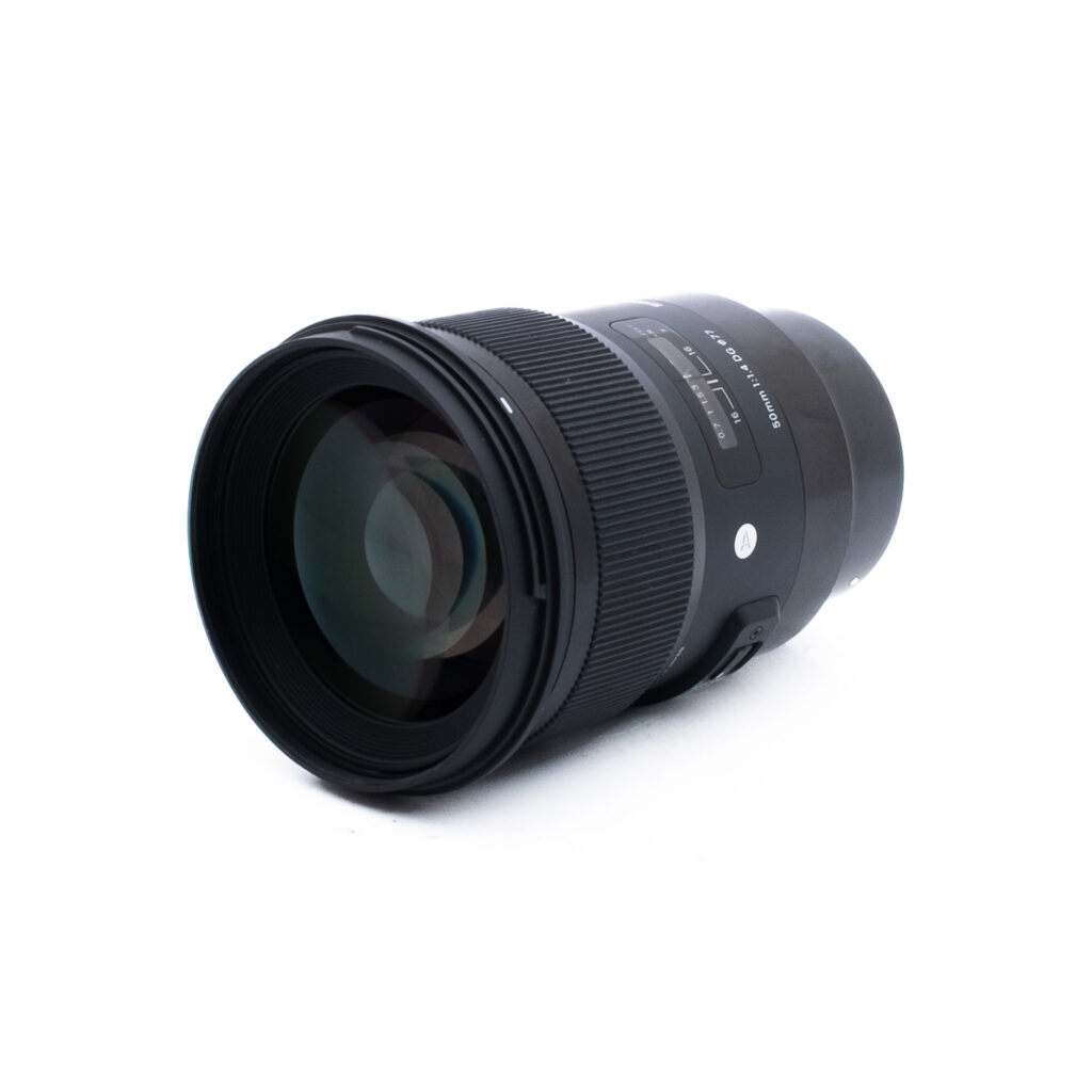 Sigma 50mm f14 DG Sony-2-2 Sigma 50mm f/1.4 Art DG Sony FE -objektiivi (sis. ALV 25,5%) - Käytetty, musta, jossa on suuri etuelementti, tarkennus- ja zoomausrenkaat sekä näkyvä tuotemerkki, sijaitsee vaakasuorassa valkoisella pohjalla.