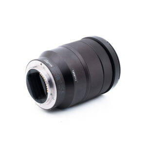 Sony 16-35mm f4 ZA OSS-1-3 Musta kameran linssi kyljellään, josta näkyy metallikiinnitys ja elektroniset kontaktit. Tynnyrissä on kuvioidut pitorenkaat ja painetut mallinumerot, eikä objektiivin lasi ole näkyvissä. Taustalla on pelkkä valkoinen.