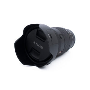 Sony 24-70mm f28 GM II-3 Sony-kameran objektiivi, johon on kiinnitetty linssinsuojus ja suojus, vinossa valkoisella taustalla.